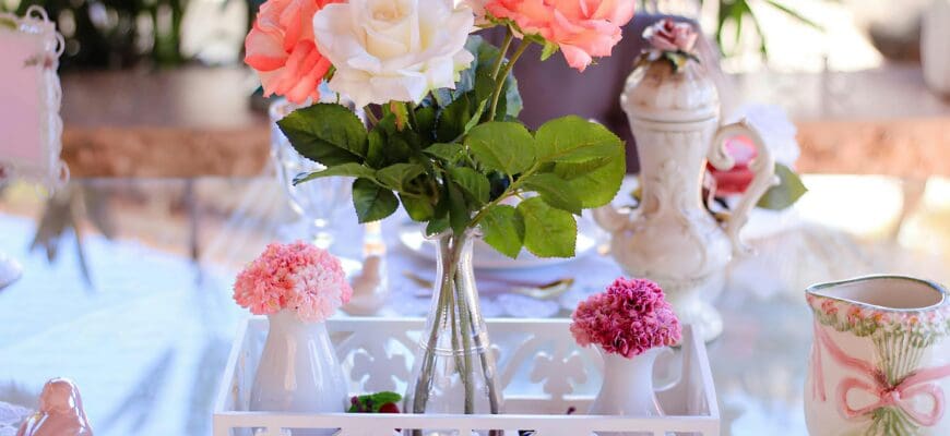 A Table set with a large vase of flowers and two small vases of flowers in a metal tray, and a bird ceramic